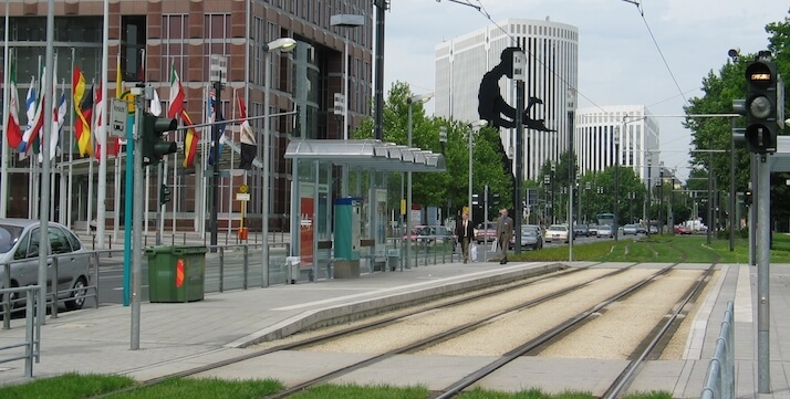 Station Festhalle / Messe. Links die verschiedenen Länderfahnen neben dem Bahnsteig vor einem Gebäude.